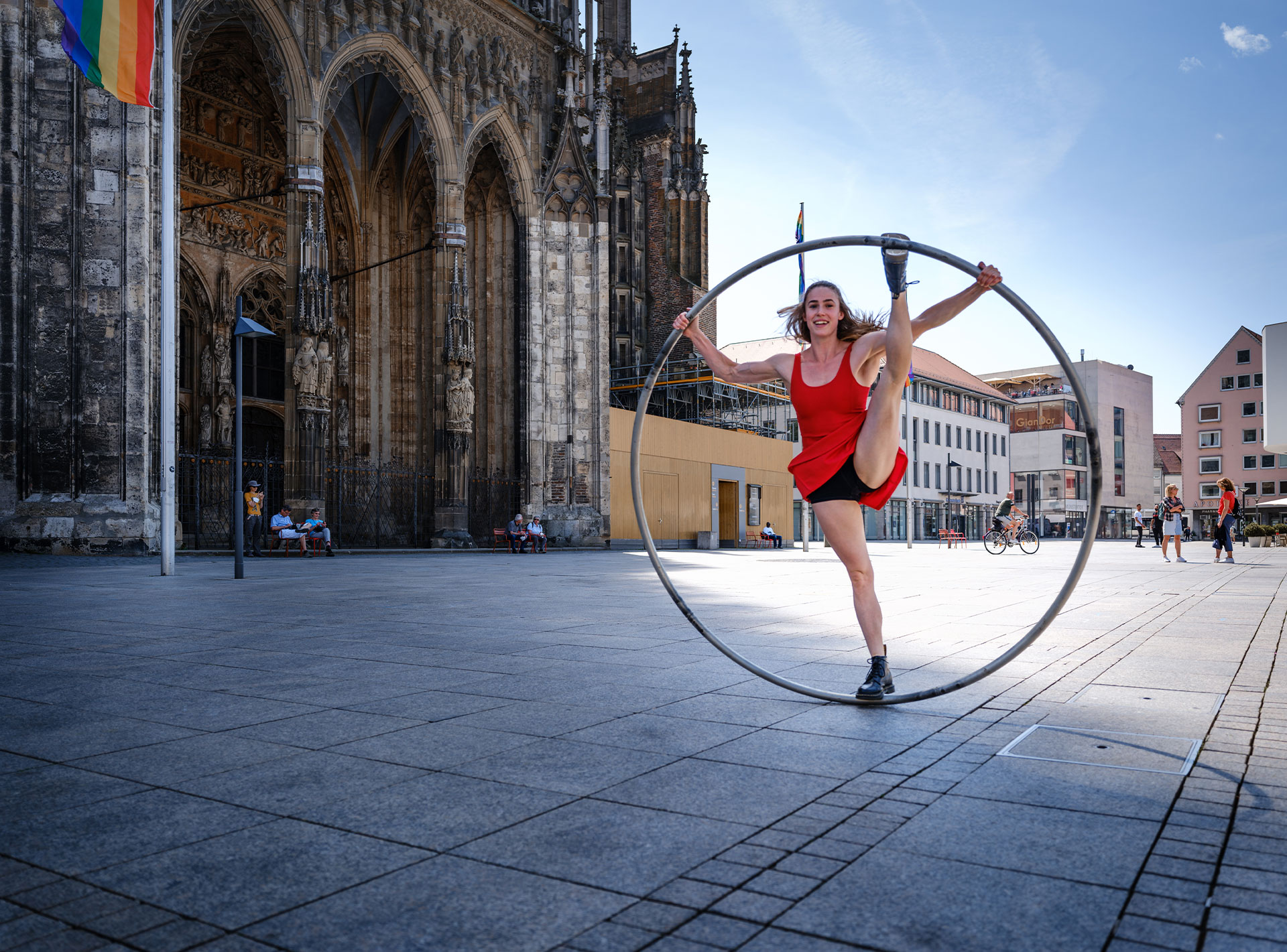 Akrobatin Lea Toran Jenner in rotem Kleid zeigt eine Übung im Cyrwheel auf dem Ulmer Münster Platz.