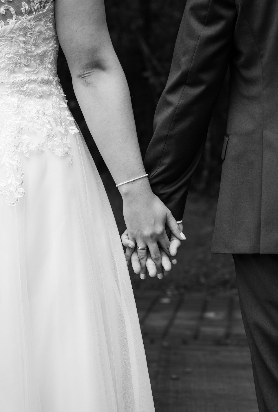 Braut und Bräutigam halten sich bei der Hochzeit die Hände.